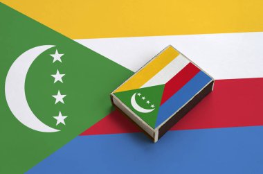 Komor bayrağı üzerinde büyük bir bayrak yatıyor bir kibrit kutusu üzerinde resimde.