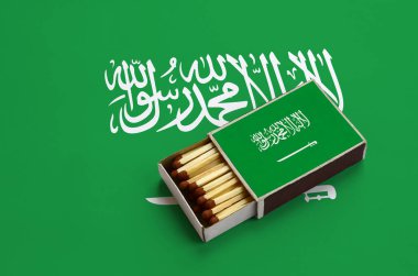 Suudi Arabistan bayrağı açık bir kibrit kutusu içinde gösterilen hangi dolu maçlar ve büyük bir bayrak üzerinde yatıyor.