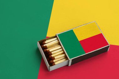 Benin bayrağı açık bir kibrit kutusu içinde gösterilen hangi dolu maçlar ve büyük bir bayrak üzerinde yatıyor.