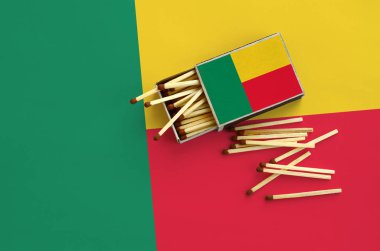 Benin bayrağı bir kibrit kutusu içinden birkaç sonbahar eşleşir ve büyük bir bayrak üzerinde yatıyor açık gösterilir.