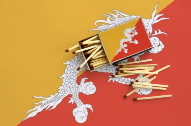 Bhutan bayrağı bir kibrit kutusu içinden birkaç sonbahar eşleşir ve büyük bir bayrak üzerinde yatıyor açık gösterilir.