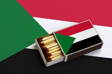 Sudan bayrağı açık bir kibrit kutusu içinde gösterilen hangi dolu maçlar ve büyük bir bayrak üzerinde yatıyor.