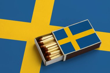 İsveç bayrağı açık bir kibrit kutusu içinde gösterilen hangi dolu maçlar ve büyük bir bayrak üzerinde yatıyor.