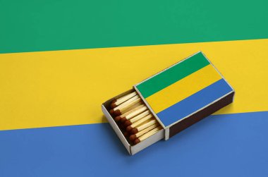 Gabon bayrak açık bir kibrit kutusu içinde gösterilen hangi dolu maçlar ve büyük bir bayrak üzerinde yatıyor.