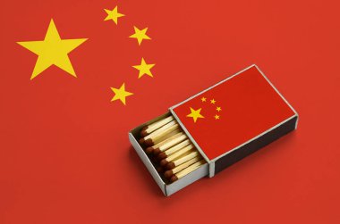 Çin bayrağı açık bir kibrit kutusu içinde gösterilen hangi dolu maçlar ve büyük bir bayrak üzerinde yatıyor.