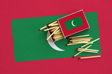 Maldivler bayrağı bir kibrit kutusu içinden birkaç sonbahar eşleşir ve büyük bir bayrak üzerinde yatıyor açık gösterilir.