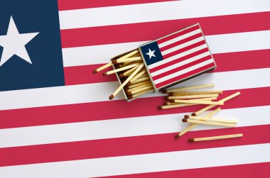 Liberya bayrağı bir kibrit kutusu içinden birkaç sonbahar eşleşir ve büyük bir bayrak üzerinde yatıyor açık gösterilir.