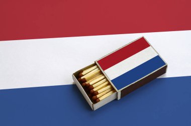 Hollanda bayrağı açık bir kibrit kutusu içinde gösterilen hangi dolu maçlar ve büyük bir bayrak üzerinde yatıyor.
