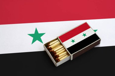 Suriye bayrağı açık bir kibrit kutusu içinde gösterilen hangi dolu maçlar ve büyük bir bayrak üzerinde yatıyor.