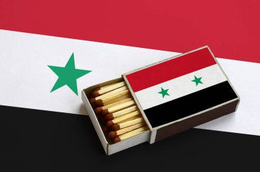 Suriye bayrağı açık bir kibrit kutusu içinde gösterilen hangi dolu maçlar ve büyük bir bayrak üzerinde yatıyor.