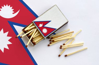 Nepal bayrağı bir kibrit kutusu içinden birkaç sonbahar eşleşir ve büyük bir bayrak üzerinde yatıyor açık gösterilir.