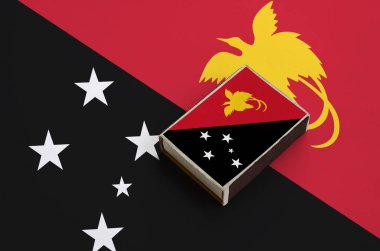 Papua Yeni Gine bayrağı üzerinde büyük bir bayrak yatıyor bir kibrit kutusu üzerinde resimde.