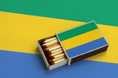 Gabon bayrak açık bir kibrit kutusu içinde gösterilen hangi dolu maçlar ve büyük bir bayrak üzerinde yatıyor.