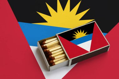 Antigua ve Barbuda bayrağı açık bir kibrit kutusu içinde gösterilen hangi dolu maçlar ve büyük bir bayrak üzerinde yatıyor.