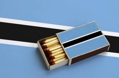 Botsvana bayrağı açık bir kibrit kutusu içinde gösterilen hangi dolu maçlar ve büyük bir bayrak üzerinde yatıyor.