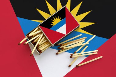 Antigua ve Barbuda bayrağı bir kibrit kutusu içinden birkaç sonbahar eşleşir ve büyük bir bayrak üzerinde yatıyor açık gösterilir.