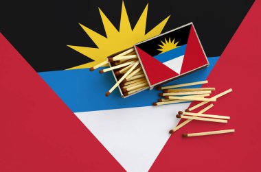 Antigua ve Barbuda bayrağı bir kibrit kutusu içinden birkaç sonbahar eşleşir ve büyük bir bayrak üzerinde yatıyor açık gösterilir.