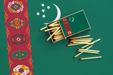 Türkmenistan bayrağı bir kibrit kutusu içinden birkaç sonbahar eşleşir ve büyük bir bayrak üzerinde yatıyor açık gösterilir.