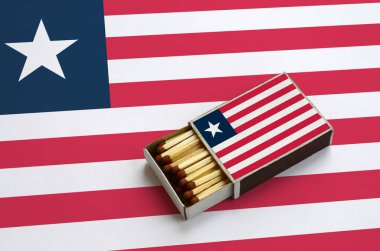 Liberya bayrağı açık bir kibrit kutusu içinde gösterilen hangi dolu maçlar ve büyük bir bayrak üzerinde yatıyor.