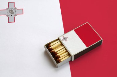 Malta bayrağı açık bir kibrit kutusu içinde gösterilen hangi dolu maçlar ve büyük bir bayrak üzerinde yatıyor.