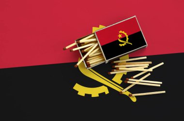 Angola bayrağı bir kibrit kutusu içinden birkaç sonbahar eşleşir ve büyük bir bayrak üzerinde yatıyor açık gösterilir.