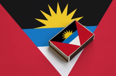 Antigua ve Barbuda bayrağı üzerinde büyük bir bayrak yatıyor bir kibrit kutusu üzerinde resimde.