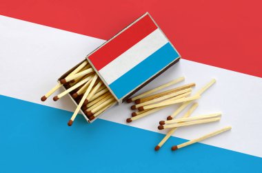 Lüksemburg bayrağı bir kibrit kutusu içinden birkaç sonbahar eşleşir ve büyük bir bayrak üzerinde yatıyor açık gösterilir.