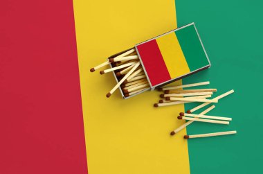 Gine bayrağı bir kibrit kutusu içinden birkaç sonbahar eşleşir ve büyük bir bayrak üzerinde yatıyor açık gösterilir.