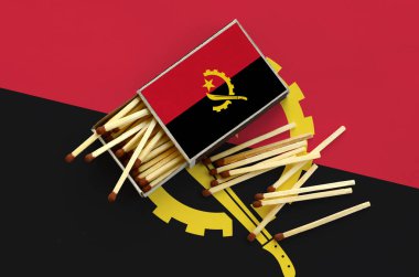Angola bayrağı bir kibrit kutusu içinden birkaç sonbahar eşleşir ve büyük bir bayrak üzerinde yatıyor açık gösterilir.