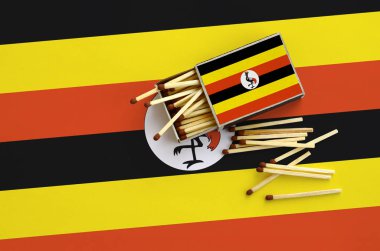 Uganda bayrağı bir kibrit kutusu içinden birkaç sonbahar eşleşir ve büyük bir bayrak üzerinde yatıyor açık gösterilir.