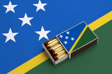 Solomon Adaları bayrağı açık bir kibrit kutusu içinde gösterilen hangi dolu maçlar ve büyük bir bayrak üzerinde yatıyor.