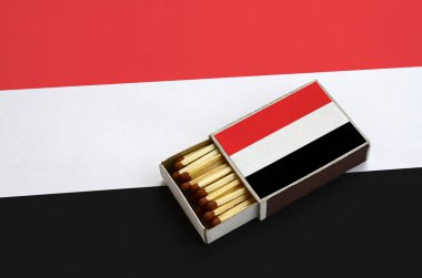 Yemen bayrak açık bir kibrit kutusu içinde gösterilen hangi dolu maçlar ve büyük bir bayrak üzerinde yatıyor.