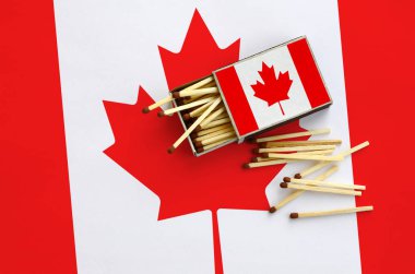 Kanada bayrağı bir kibrit kutusu içinden birkaç sonbahar eşleşir ve büyük bir bayrak üzerinde yatıyor açık gösterilir.