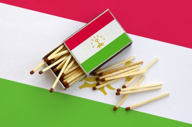 Tacikistan bayrağı bir kibrit kutusu içinden birkaç sonbahar eşleşir ve büyük bir bayrak üzerinde yatıyor açık gösterilir.