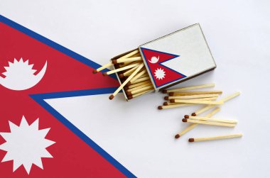 Nepal bayrağı bir kibrit kutusu içinden birkaç sonbahar eşleşir ve büyük bir bayrak üzerinde yatıyor açık gösterilir.