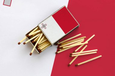 Malta bayrağı bir kibrit kutusu içinden birkaç sonbahar eşleşir ve büyük bir bayrak üzerinde yatıyor açık gösterilir.