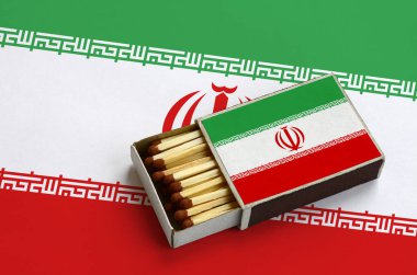 Iran bayrağı açık bir kibrit kutusu içinde gösterilen hangi dolu maçlar ve büyük bir bayrak üzerinde yatıyor.