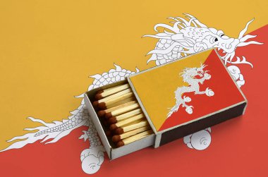 Bhutan bayrağı açık bir kibrit kutusu içinde gösterilen hangi dolu maçlar ve büyük bir bayrak üzerinde yatıyor.