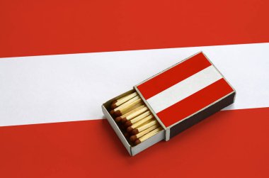 Avusturya bayrağı açık bir kibrit kutusu içinde gösterilen hangi dolu maçlar ve büyük bir bayrak üzerinde yatıyor.