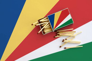 Seyşel Adaları bayrağı bir kibrit kutusu içinden birkaç sonbahar eşleşir ve büyük bir bayrak üzerinde yatıyor açık gösterilir.