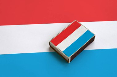 Lüksemburg bayrağı üzerinde büyük bir bayrak yatıyor bir kibrit kutusu üzerinde resimde.