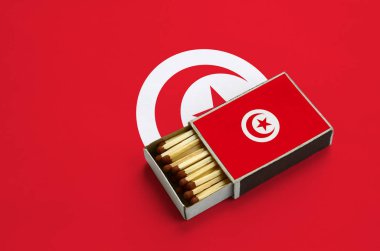 Tunus bayrağı açık bir kibrit kutusu içinde gösterilen hangi dolu maçlar ve büyük bir bayrak üzerinde yatıyor.