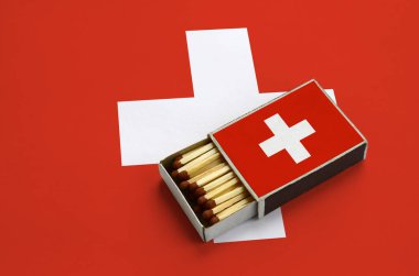 İsviçre bayrağı açık bir kibrit kutusu içinde gösterilen hangi dolu maçlar ve büyük bir bayrak üzerinde yatıyor.