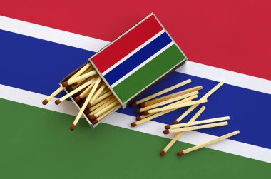 Gambiya bayrak bir kibrit kutusu içinden birkaç sonbahar eşleşir ve büyük bir bayrak üzerinde yatıyor açık gösterilir.