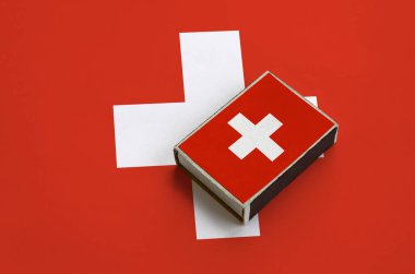 İsviçre bayrağı üzerinde büyük bir bayrak yatıyor bir kibrit kutusu üzerinde resimde.