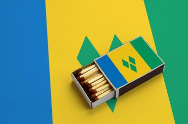 Saint Vincent ve Grenadinler bayrak açık bir kibrit kutusu içinde gösterilen hangi dolu maçlar ve büyük bir bayrak üzerinde yatıyor.