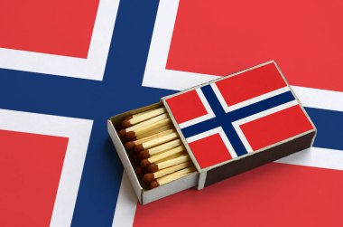 Norveç bayrağı açık bir kibrit kutusu içinde gösterilen hangi dolu maçlar ve büyük bir bayrak üzerinde yatıyor.