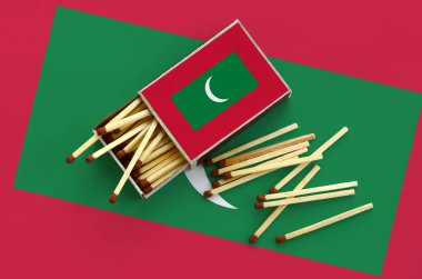Maldivler bayrağı bir kibrit kutusu içinden birkaç sonbahar eşleşir ve büyük bir bayrak üzerinde yatıyor açık gösterilir.
