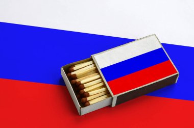 Rusya bayrağı açık bir kibrit kutusu içinde gösterilen hangi dolu maçlar ve büyük bir bayrak üzerinde yatıyor.