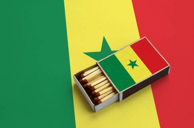 Senegal bayrak açık bir kibrit kutusu içinde gösterilen hangi dolu maçlar ve büyük bir bayrak üzerinde yatıyor.